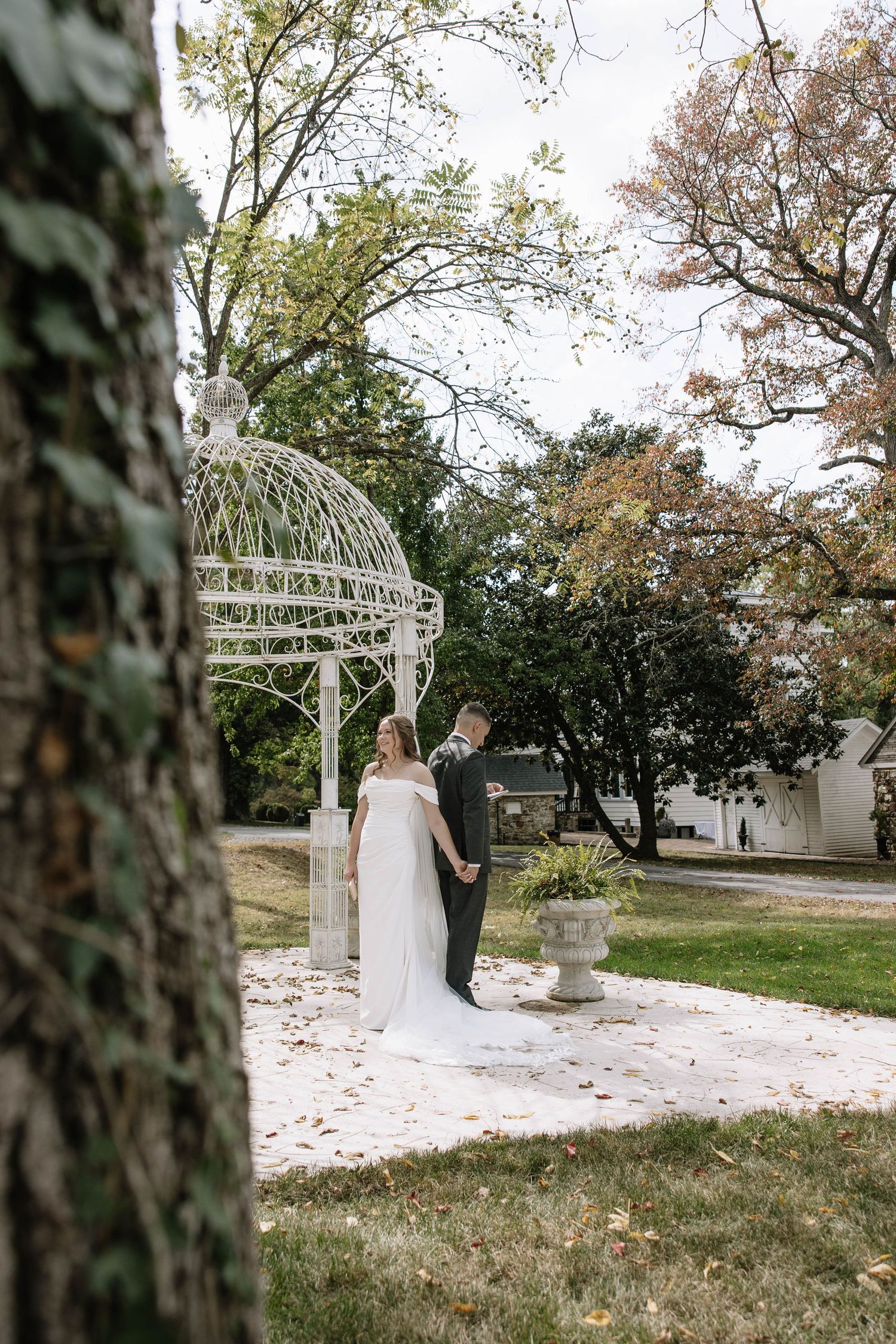 An outdoor wedding ceremony setup with white chairs and arbor surrounded by autumn trees.