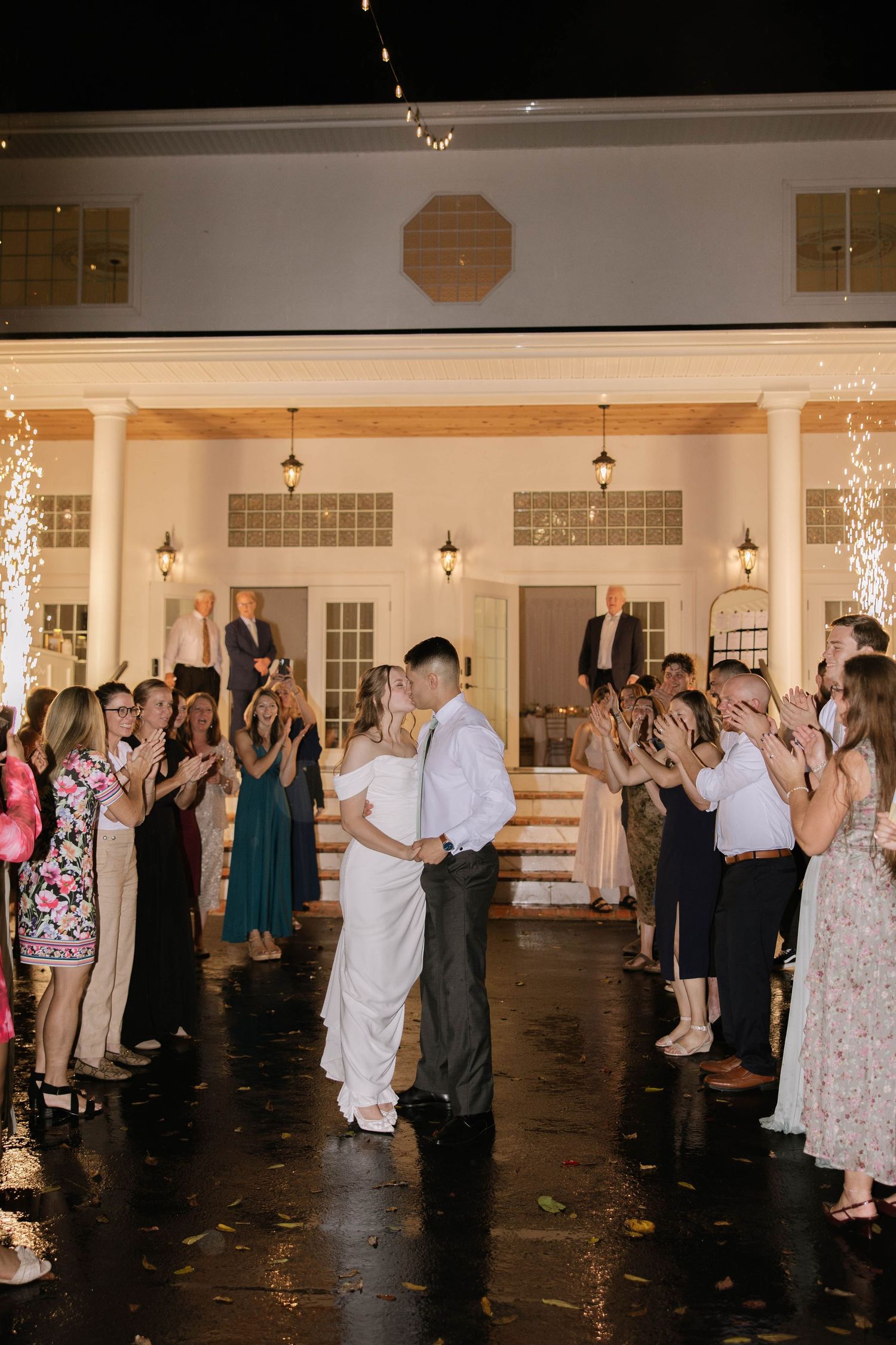 Wedding guests dancing in a large reception hall with sparkler effects creating a magical atmosphere.