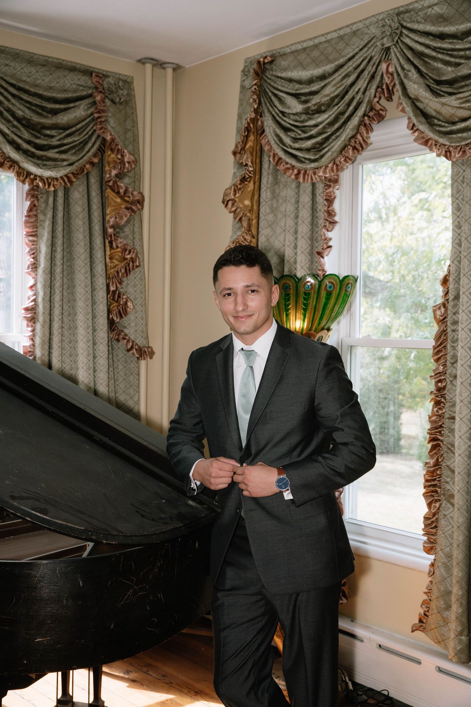 Elegant room with ornate curtains and a grand piano near large windows.