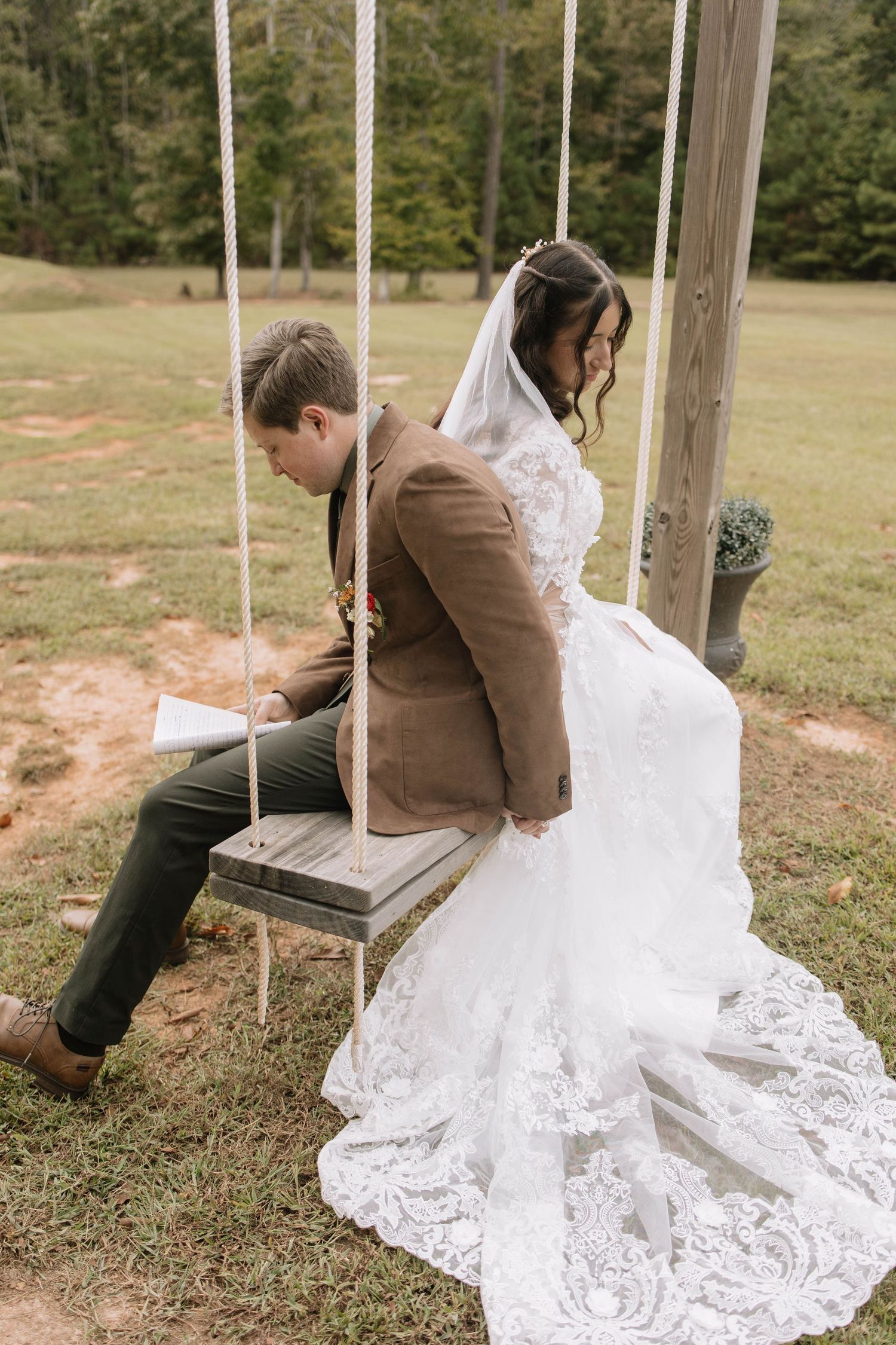 Wedding dress with lace details spread across wooden swings in an outdoor setting.
