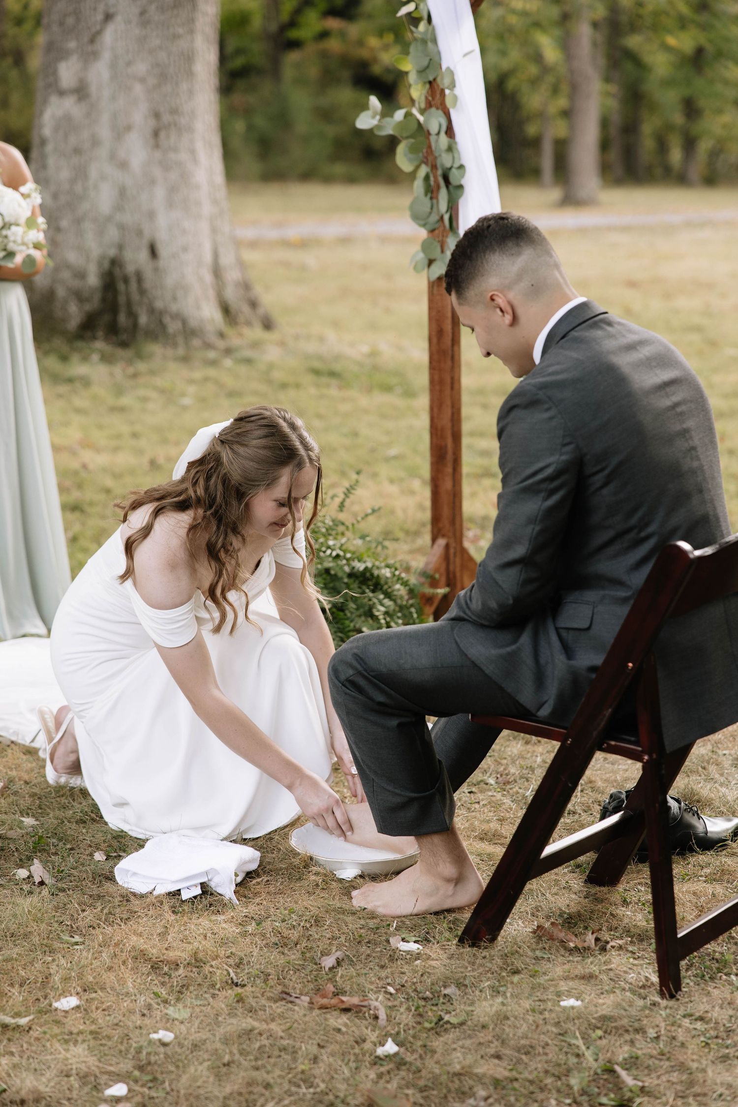 Wedding couple participates in playful garter removal tradition under decorated arch.