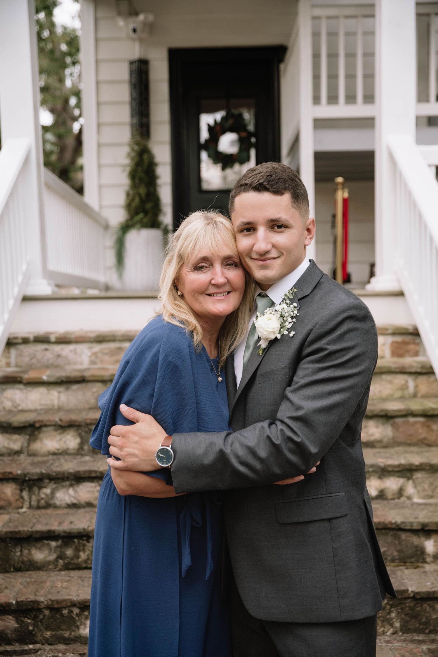 A sweet embrace captured in multiple frames showing a couple in navy blue dress and grey suit at a stone staircase.