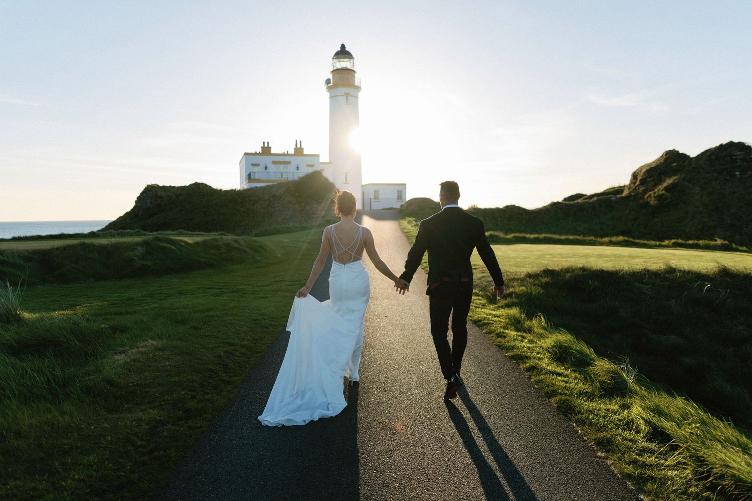 Silhouette of newlyweds walking towards lighthouse at sunset Trump Turnberry Wedding