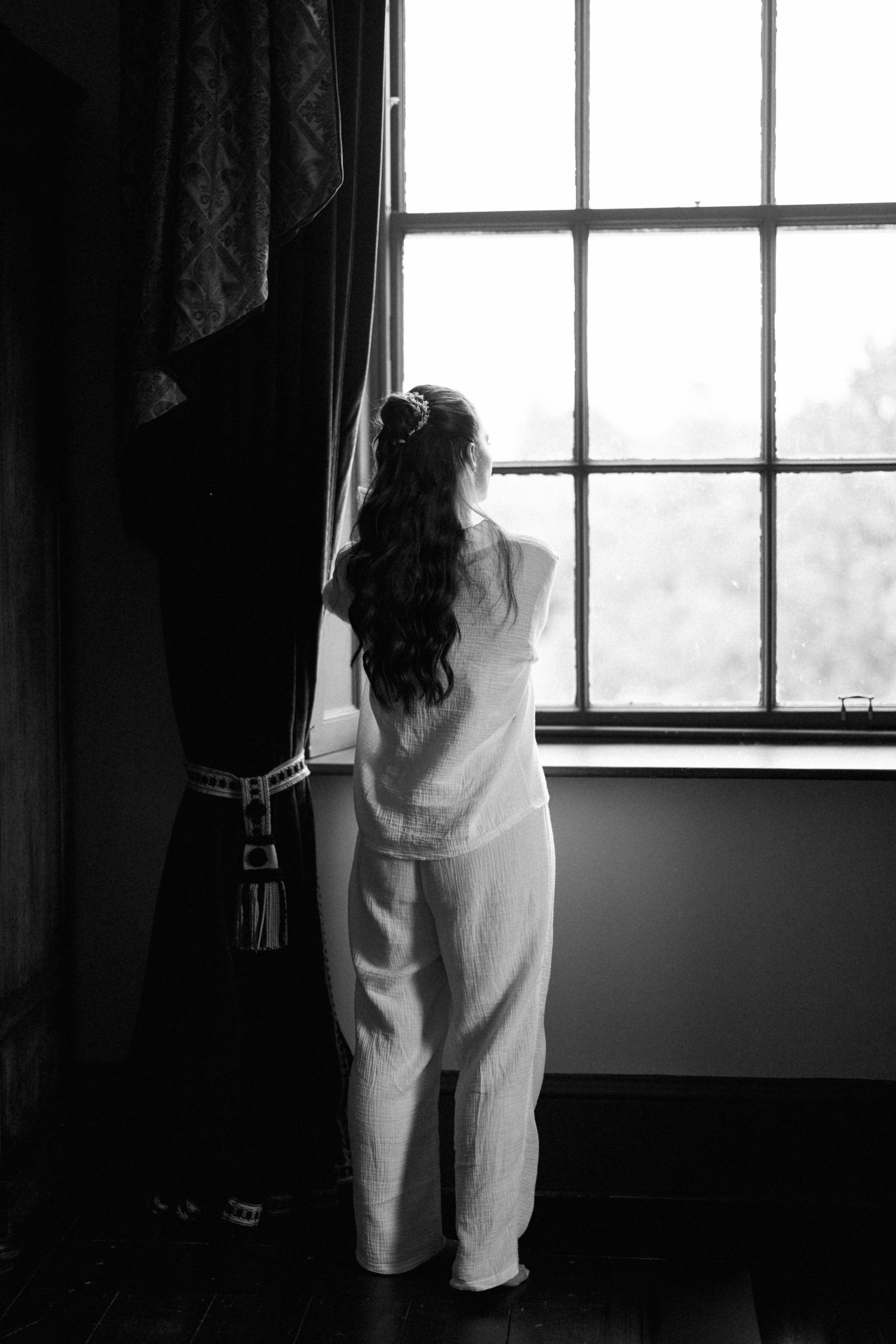 A black and white series of photos showing a person in white clothing standing by a window in silhouette.