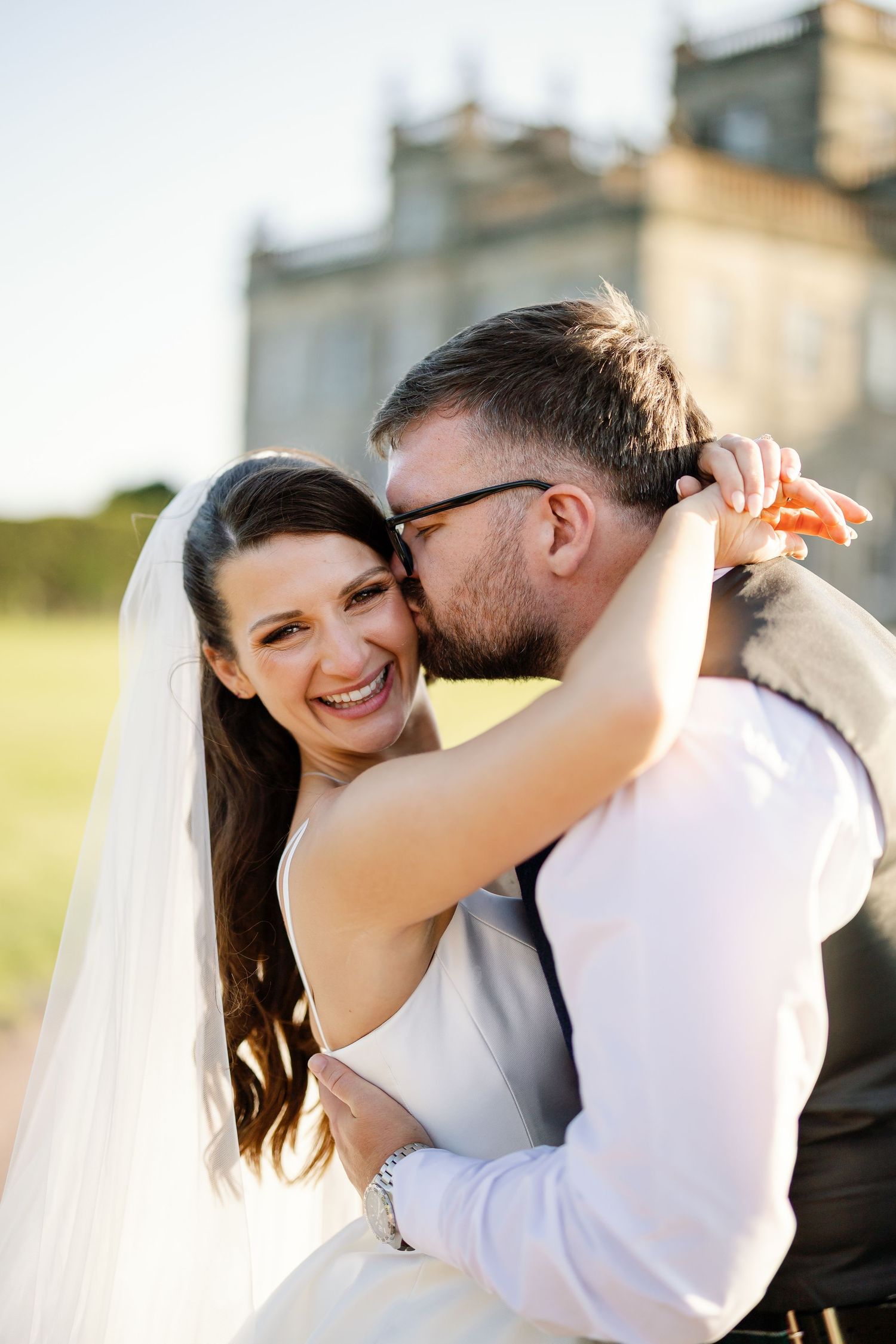 “Bride and groom standing in front of Kinmount House, a stately Scottish mansion with sweeping lawns and classic architecture.”