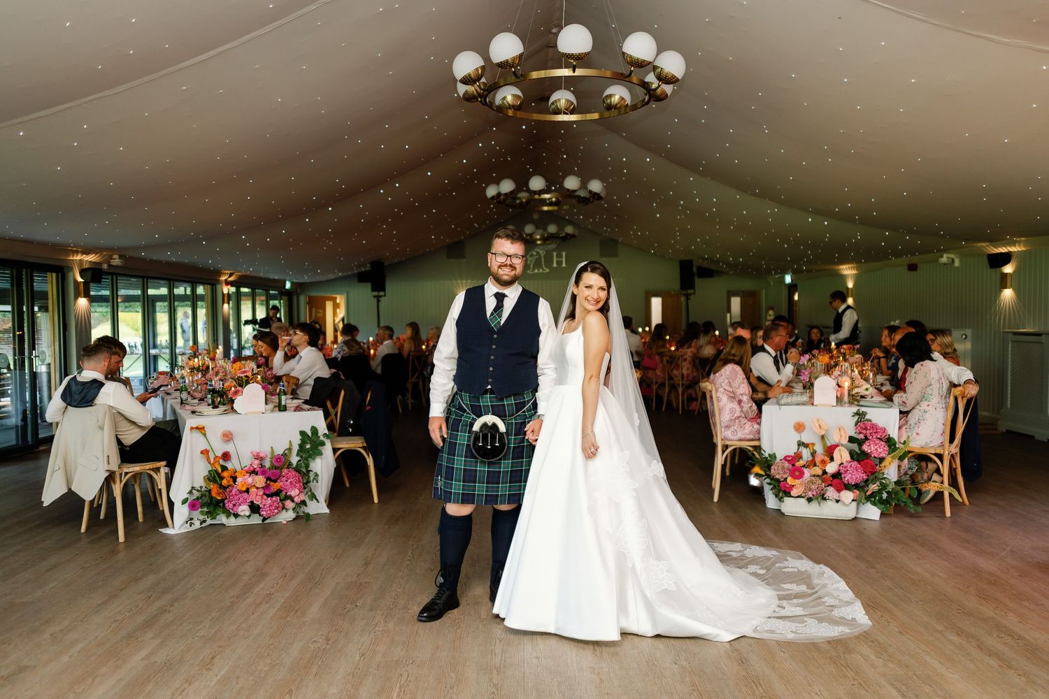 A wedding celebration in a spacious reception venue with elegant decor and tables set for guests.