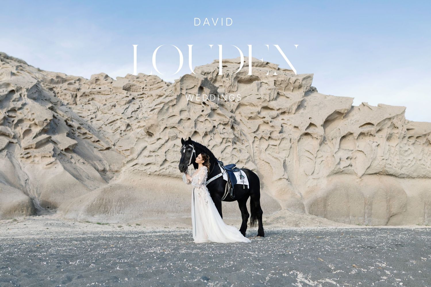 Dramatic wedding photo featuring bride in white dress with black horse against rocky desert landscape. Santorini wedding photographer