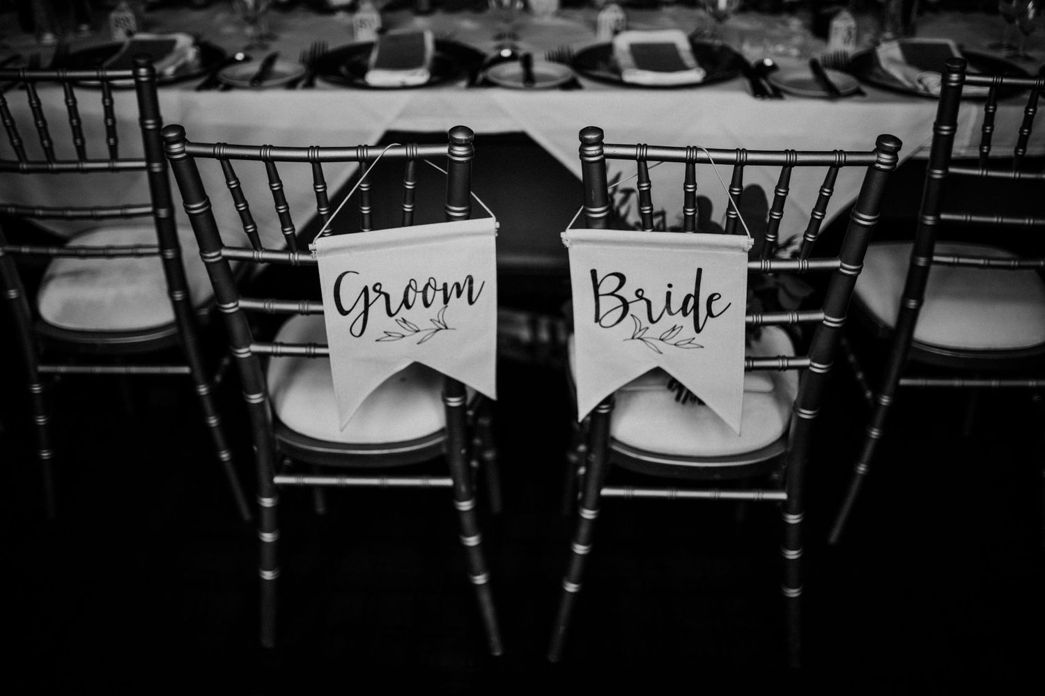 Black and white wedding reception detail showing elegant Chiavari chairs with Bride and Groom signs on white cushions.
