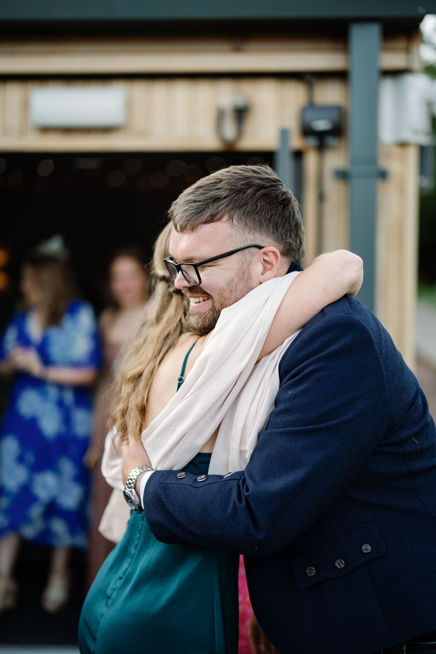 Two people share an emotional embrace while wearing formal attire at an event.