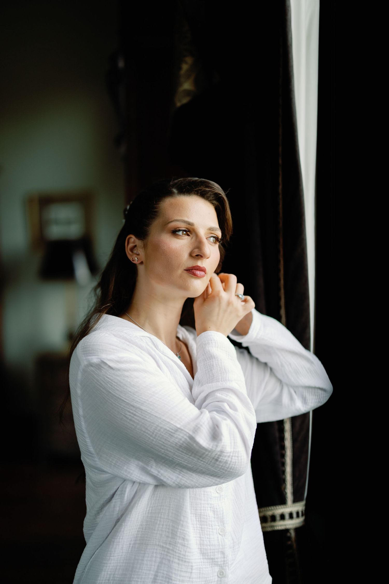 A person in a white button-down shirt leans against a window frame in a series of moody portrait shots.