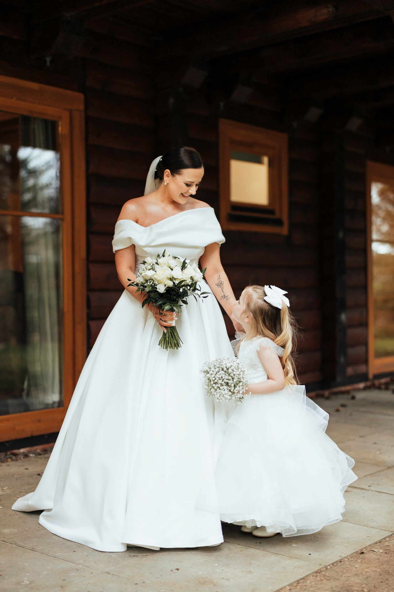 Wedding portrait of matching white gowns and floral bouquets against rustic wooden backdrop Piperdam wedding Scottish wedding