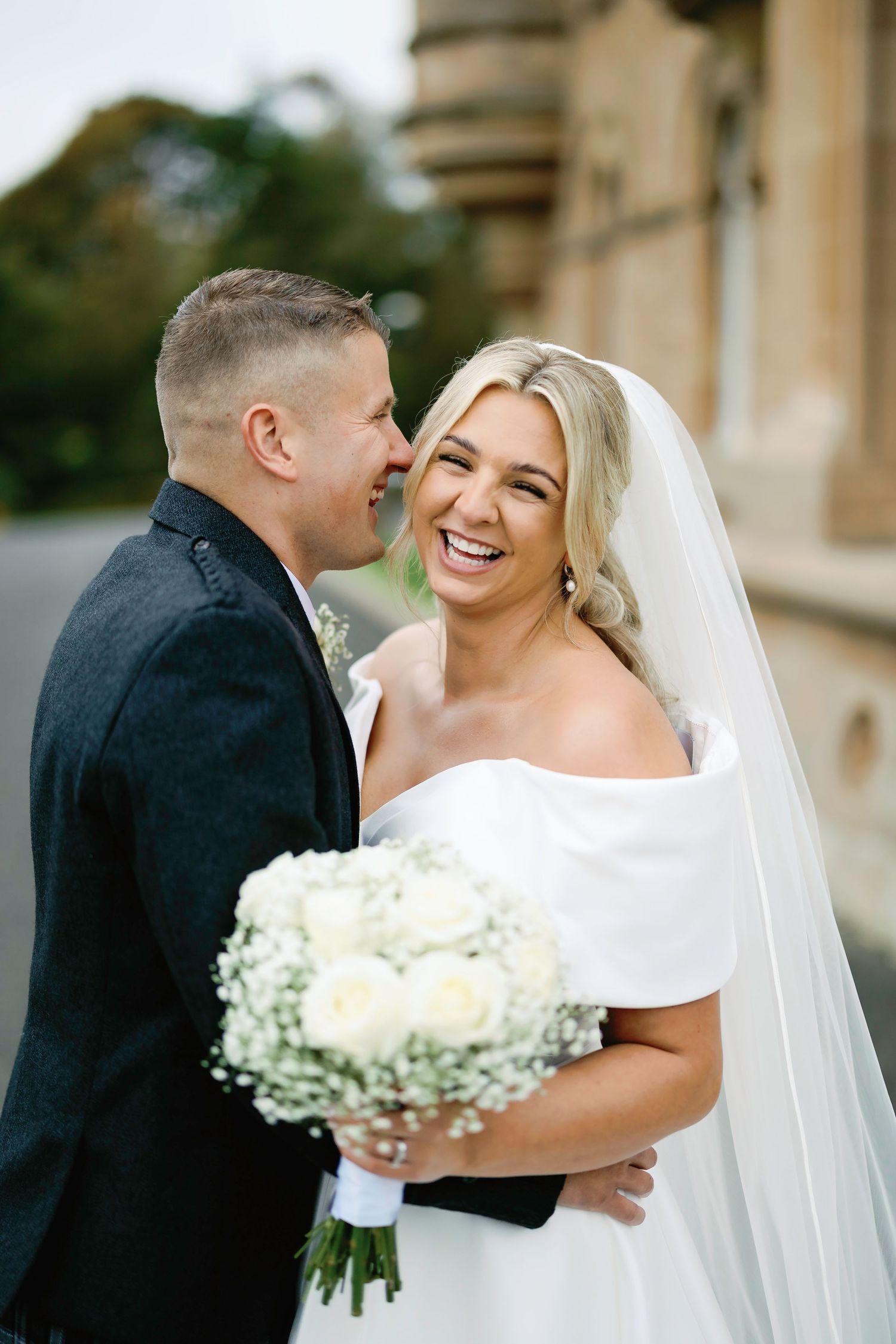 Newlyweds share romantic moments together in a series of wedding photos featuring white florals and classic formal attire.