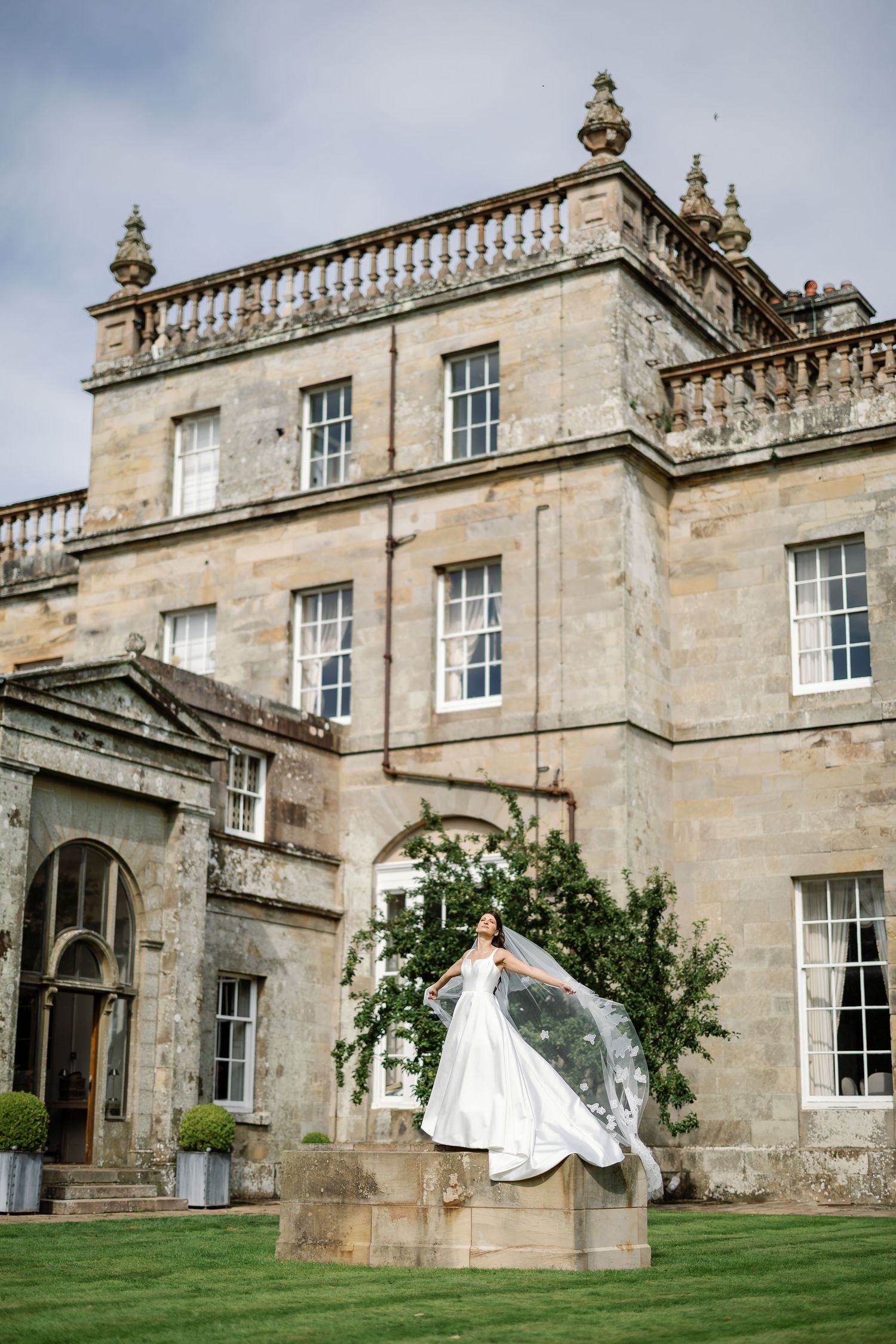 “Newlyweds walking through the gardens of Kinmount House in Scotland, surrounded by natural greenery and timeless architecture.”