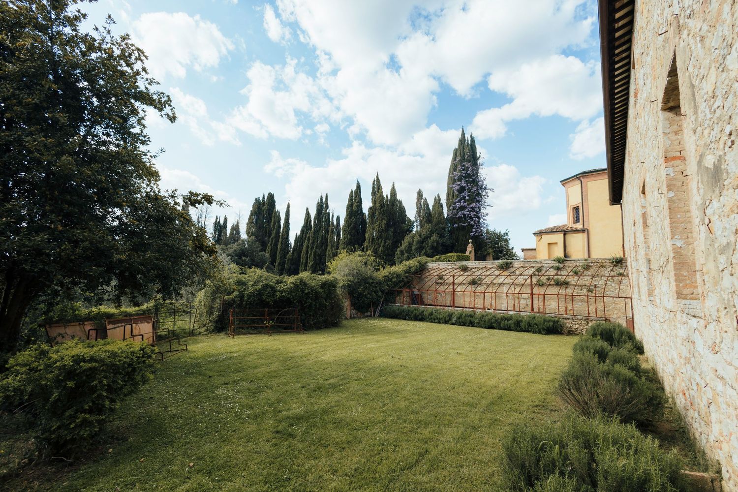 Scenic Tuscan garden with cypress trees and stone walls under blue sky. wedding photography Villa villa catignano