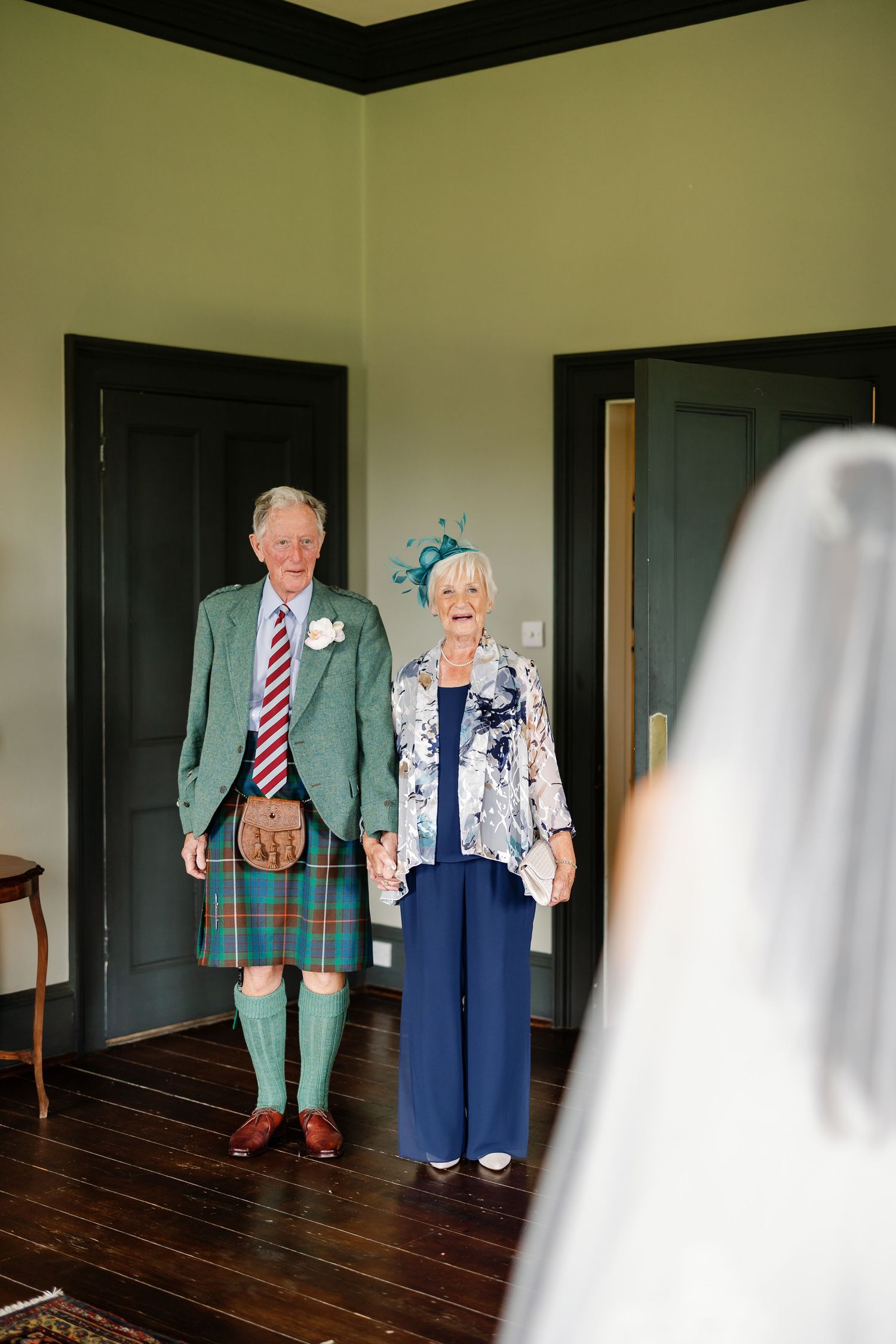 A series of connected photos showing two dolls in formal attire standing together on a dark wooden floor.