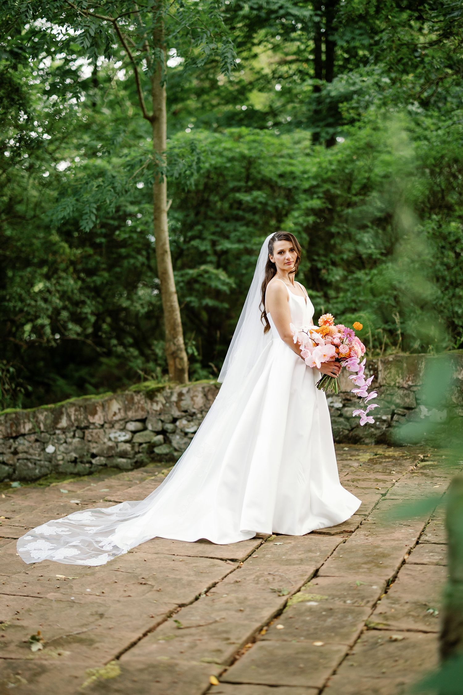 “Newlyweds walking through the gardens of Kinmount House in Scotland, surrounded by natural greenery and timeless architecture.”