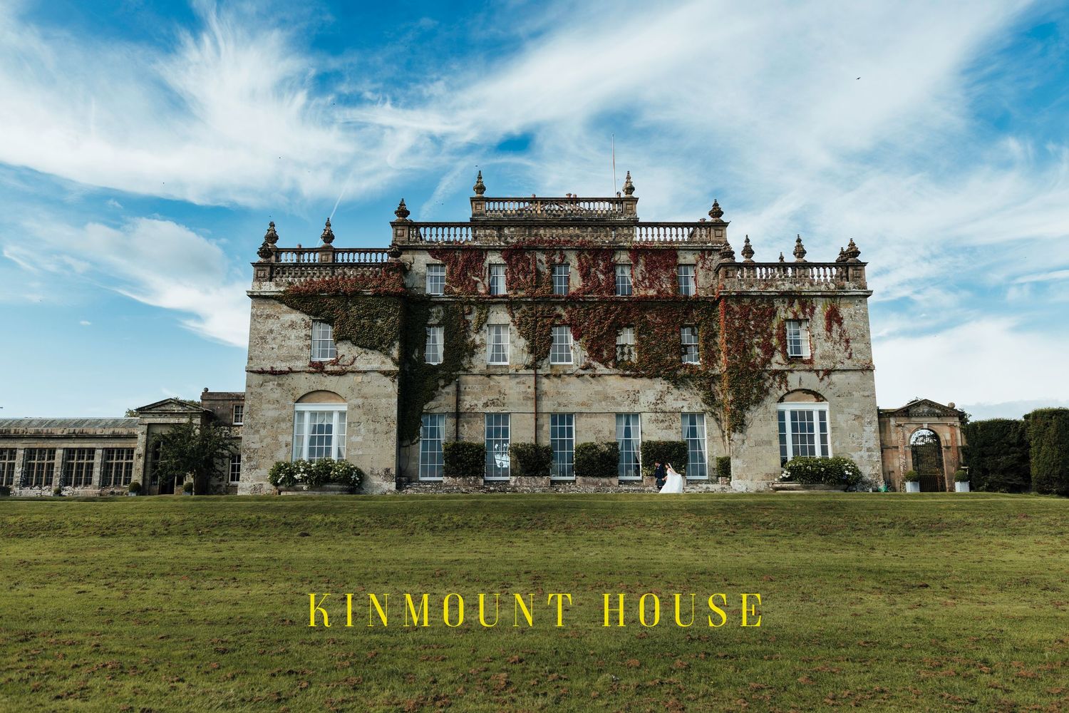 Stately Kinmount House estate building with ornate architecture set against blue sky and green lawn in Scotland.