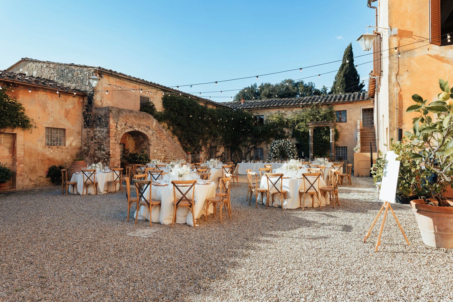 Rustic outdoor wedding reception setup with covered chairs in Italian courtyard at a Villa Catignano Wedding