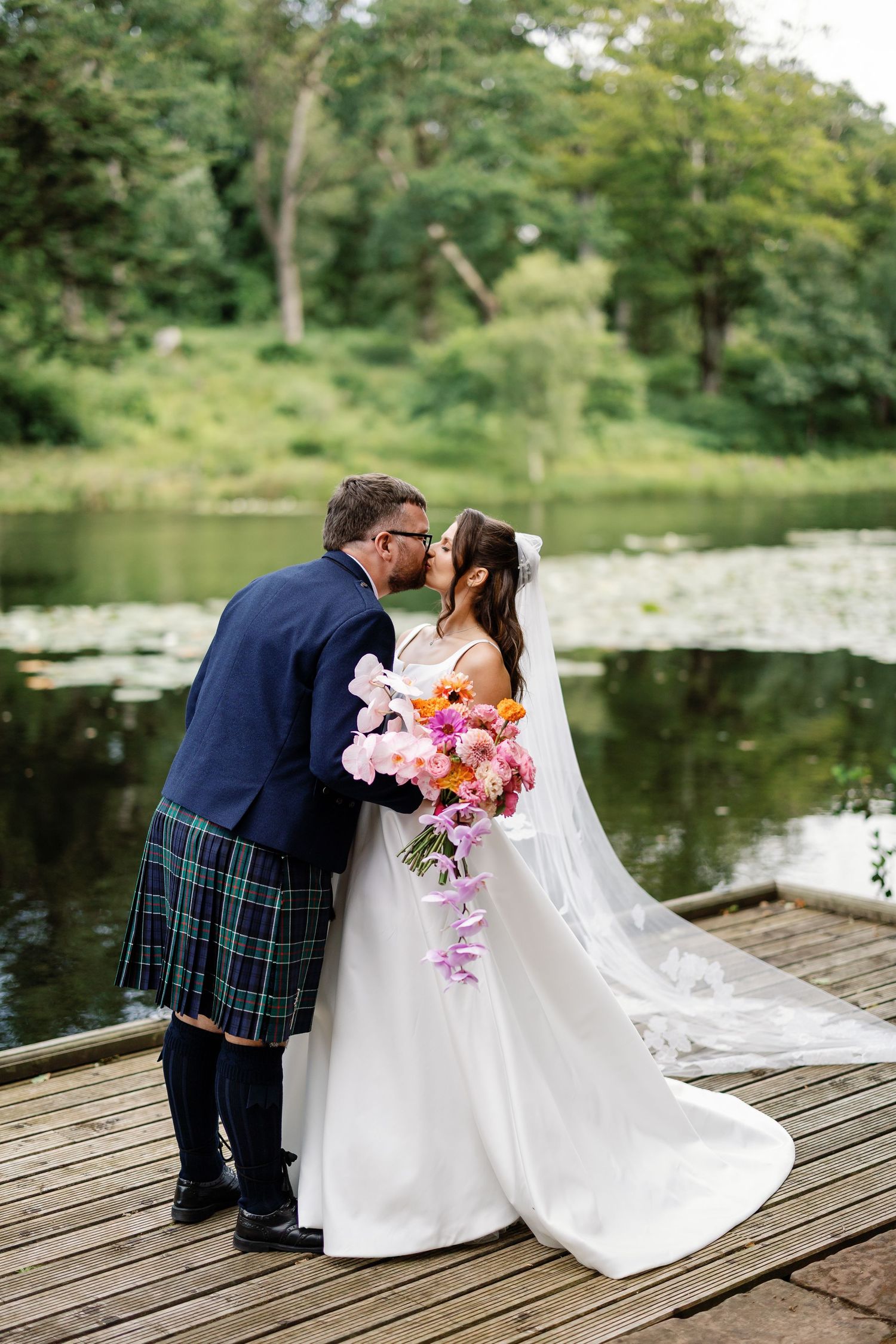 “Newlyweds walking through the gardens of Kinmount House in Scotland, surrounded by natural greenery and timeless architecture.”