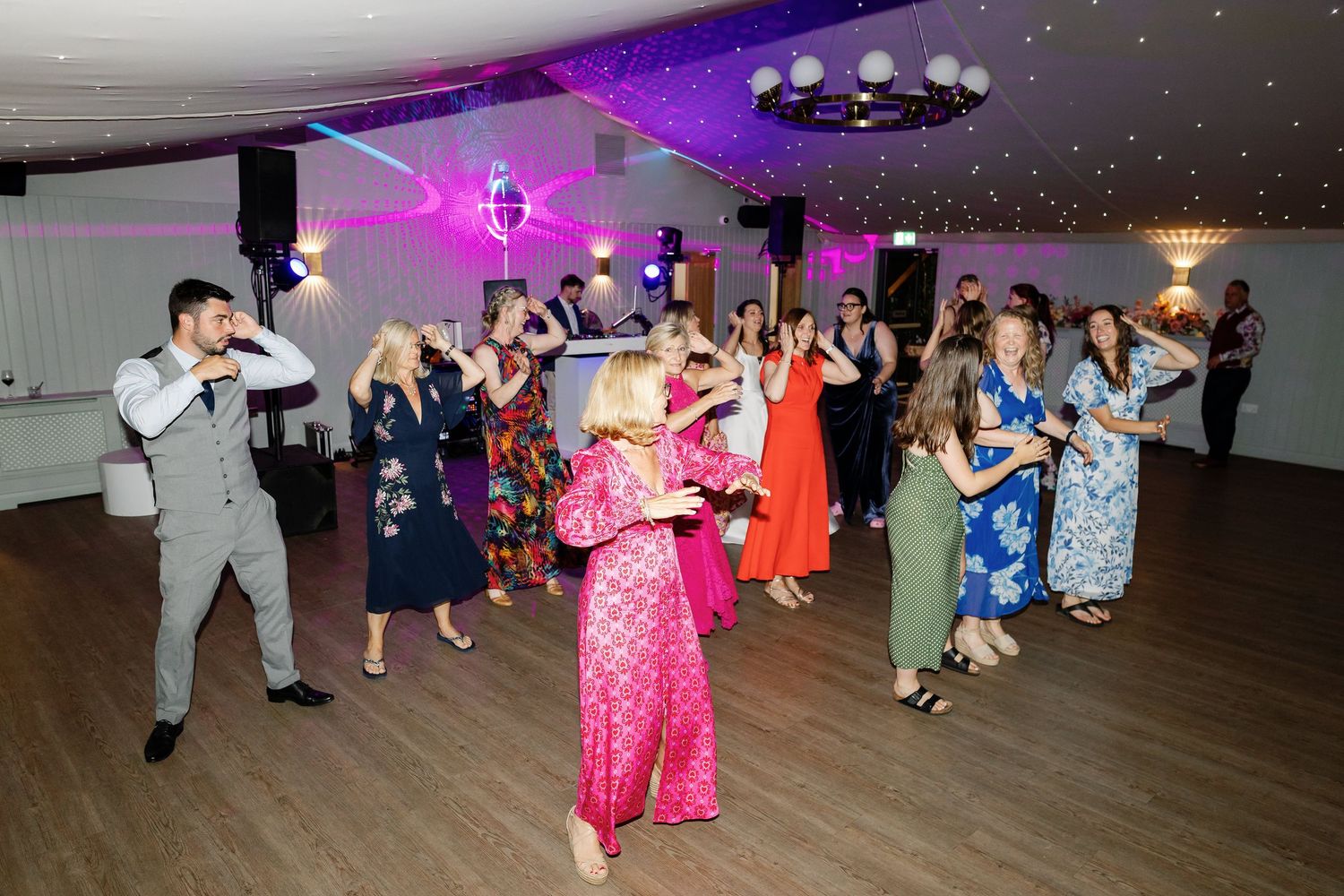 Couples dancing together in a ballroom with purple lighting and festive decorations.