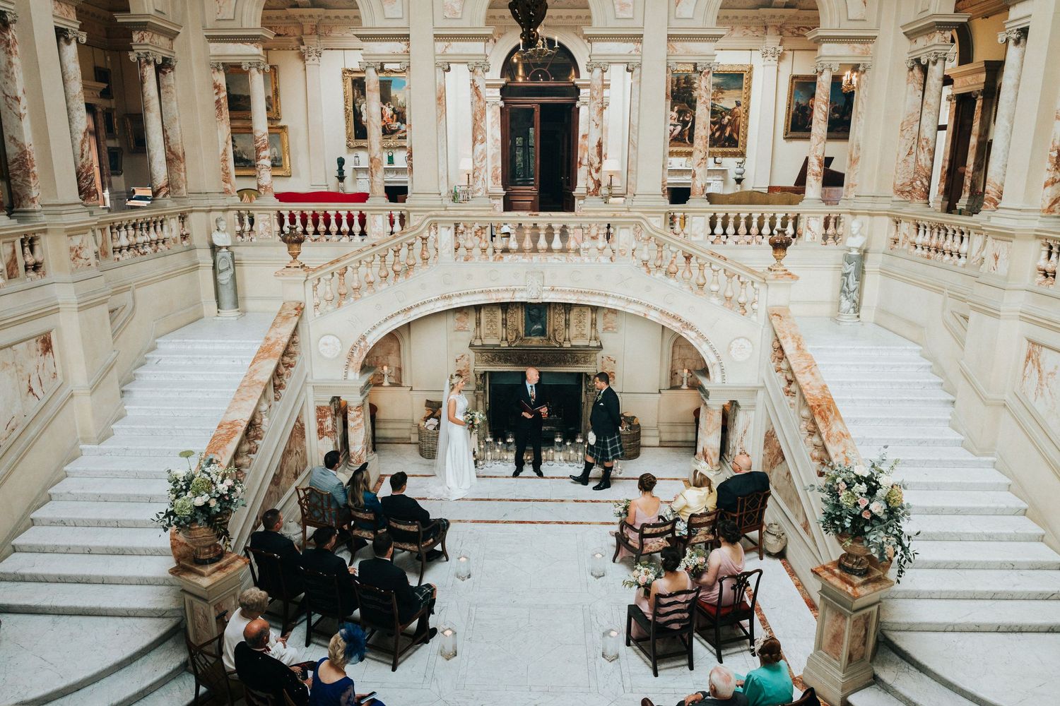 Elegant marble staircase and grand interior architecture of historic building with people gathered in foyer area.