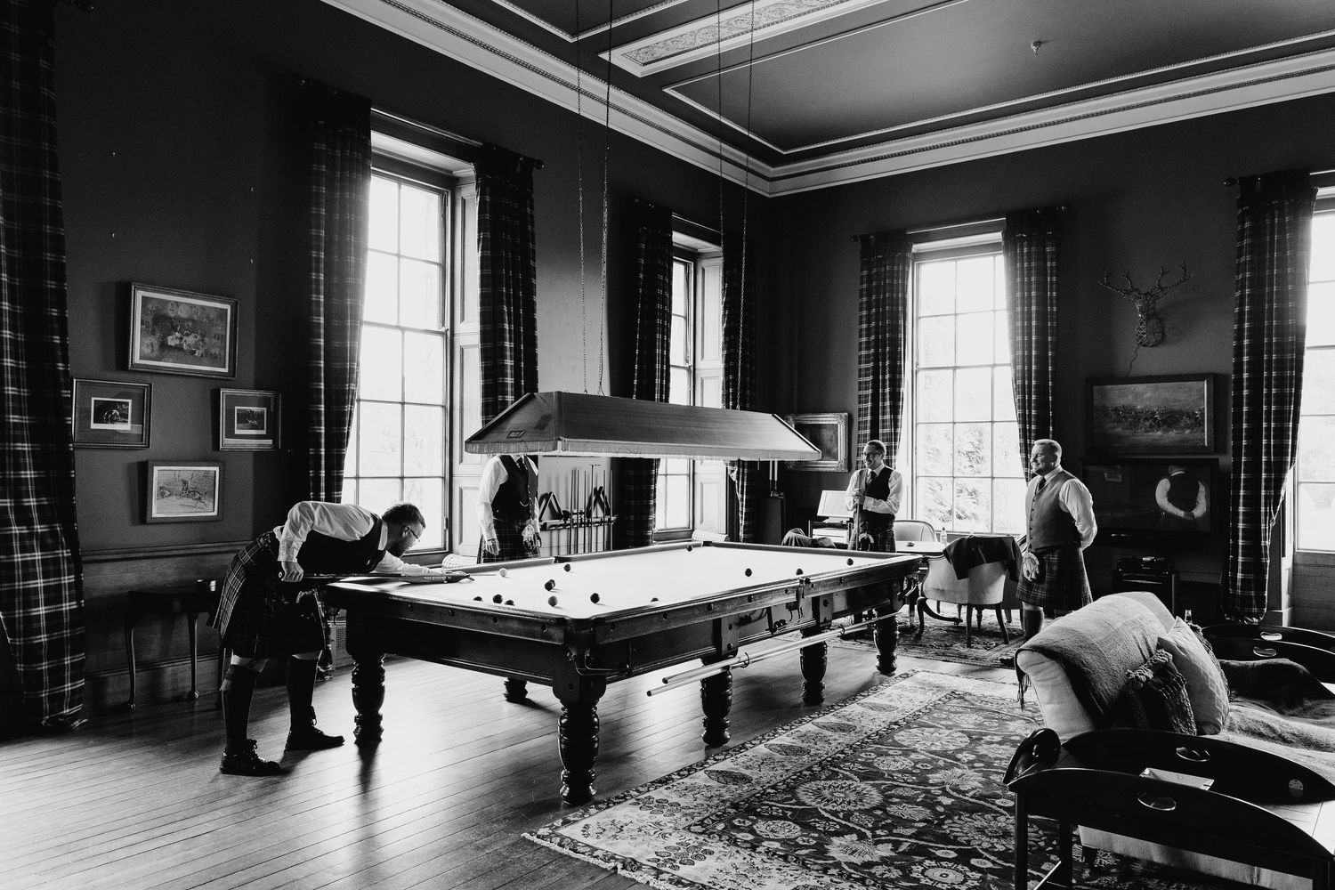 A panoramic black and white view of an elegant Victorian-era room with ornate furnishings and tall windows.