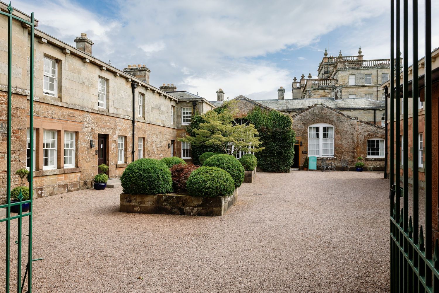 Elegant courtyard with gravel path and manicured shrubs surrounded by traditional stone buildings in Edinburgh.