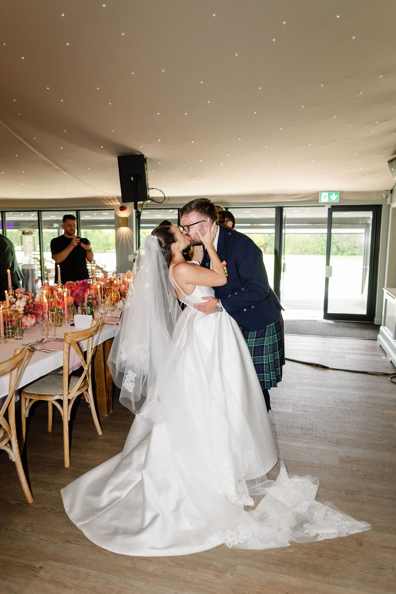 A romantic wedding couple shares a tender dip kiss on the dance floor of a modern reception venue.