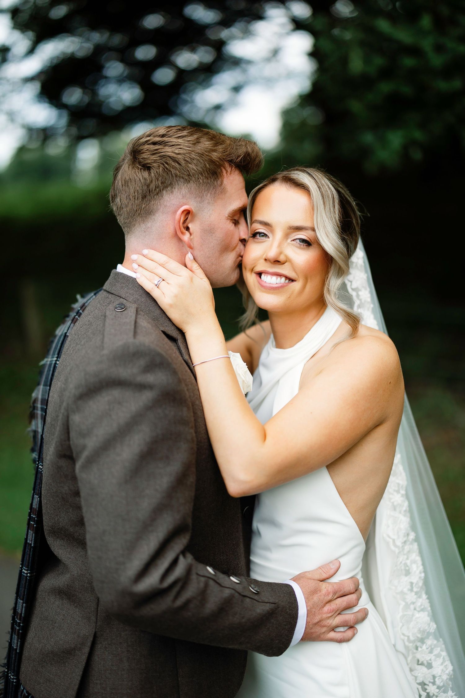 A romantic moment captured between a bride in white and groom in dark suit during an outdoor wedding ceremony.