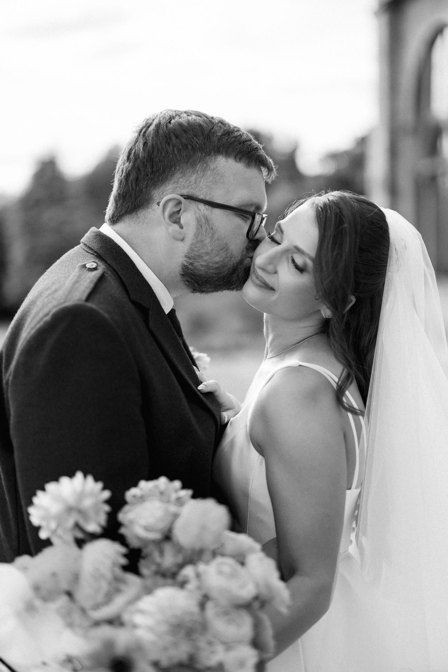 “Newlyweds walking through the gardens of Kinmount House in Scotland, surrounded by natural greenery and timeless architecture.”