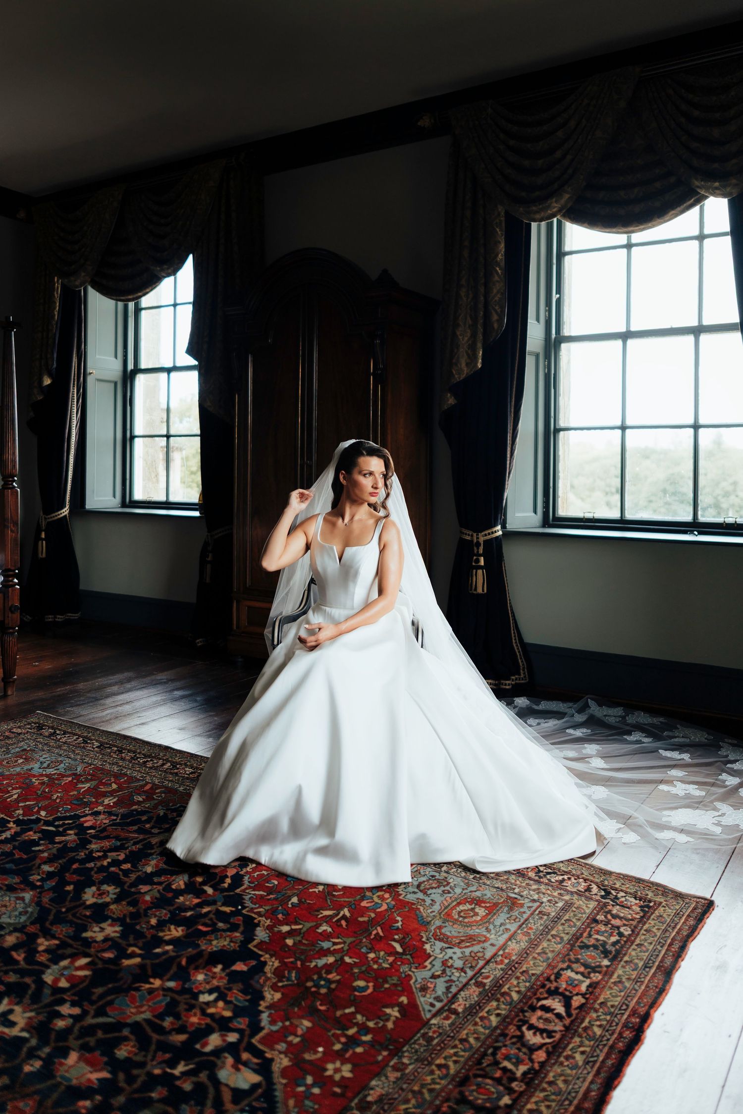 Artistic bridal portraits taken in an elegant room with ornate carpets and large windows.