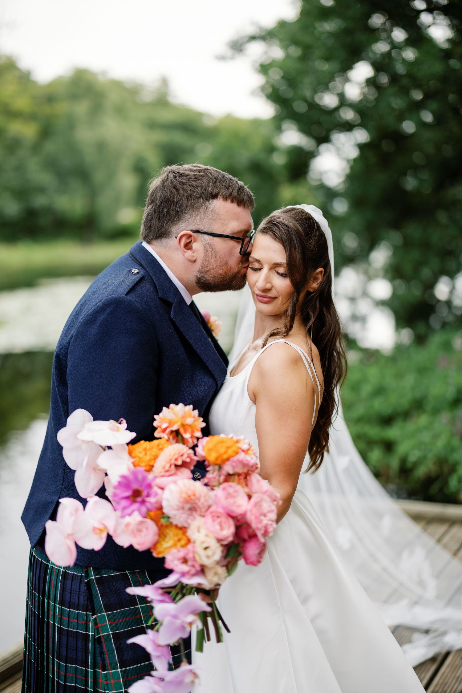 “Newlyweds walking through the gardens of Kinmount House in Scotland, surrounded by natural greenery and timeless architecture.”