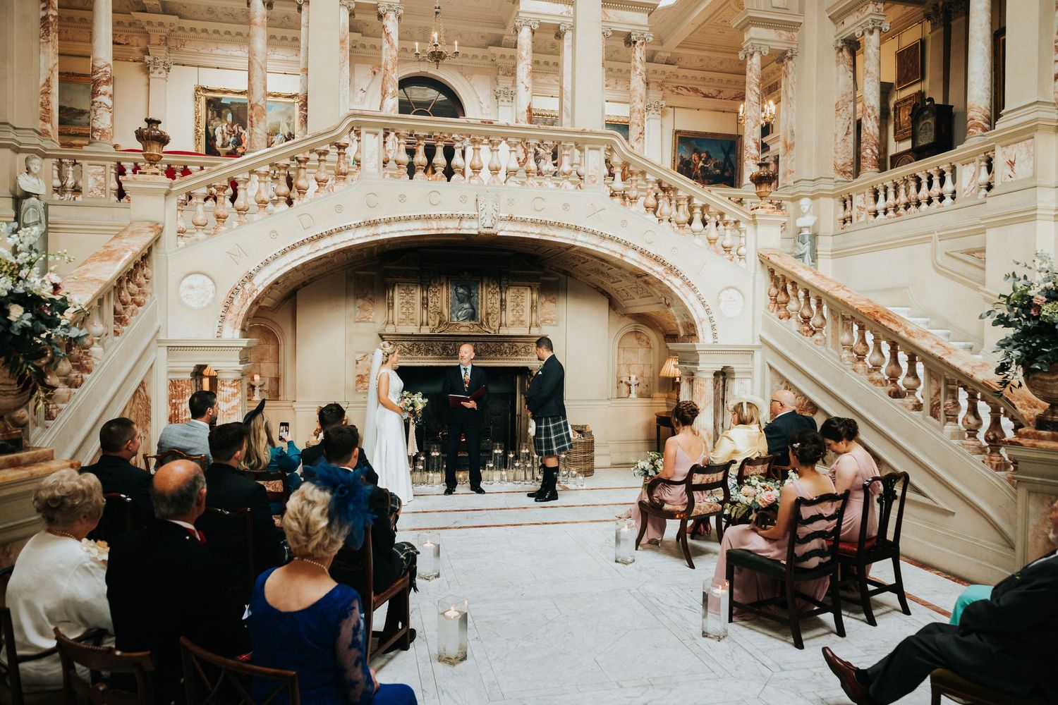 People seated at an elegant marble staircase during a ceremony in an ornate historic building interior.