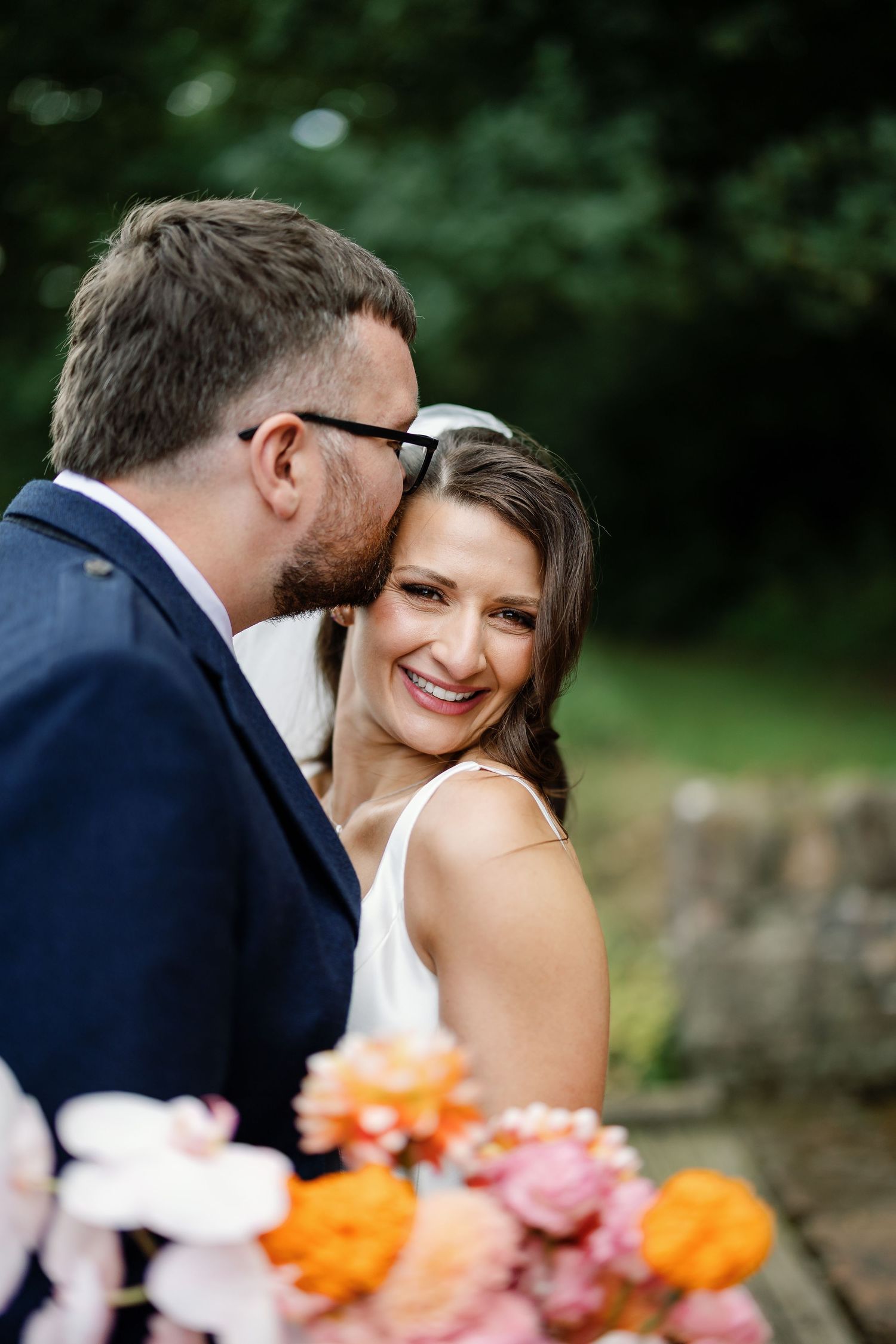 “Newlyweds walking through the gardens of Kinmount House in Scotland, surrounded by natural greenery and timeless architecture.”