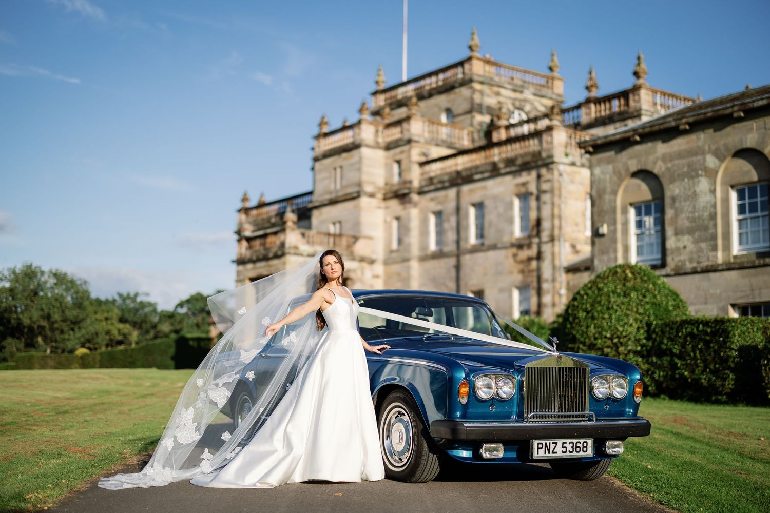 “Bride and groom standing in front of Kinmount House, a stately Scottish mansion with sweeping lawns and classic architecture.”