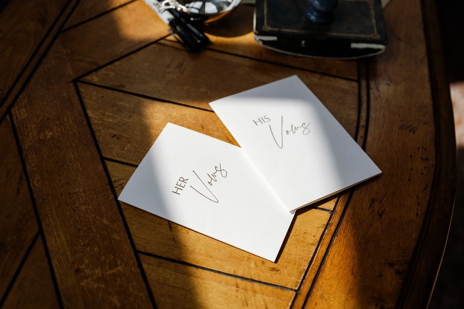 Handwritten letters and papers scattered on a wooden table illuminated by warm sunlight.