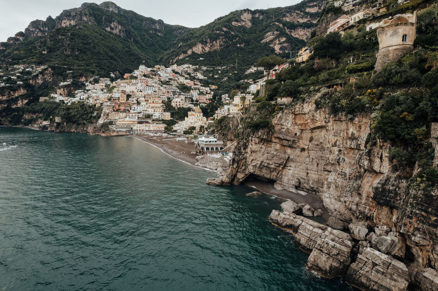 Aerial view of Positano village perched on dramatic cliffs along Italy's stunning Amalfi Coast with turquoise waters below.