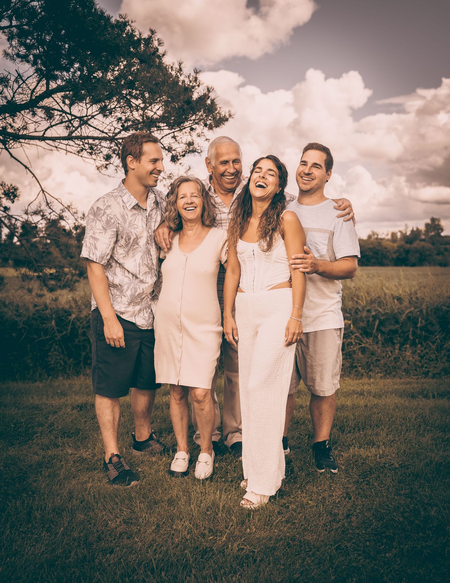 Family members share a candid laughing moment together outdoors on a sunny day.
