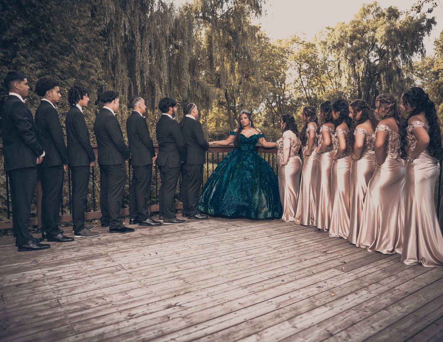 Wedding party poses on deck with bridesmaids in blush and groomsmen in black suits.