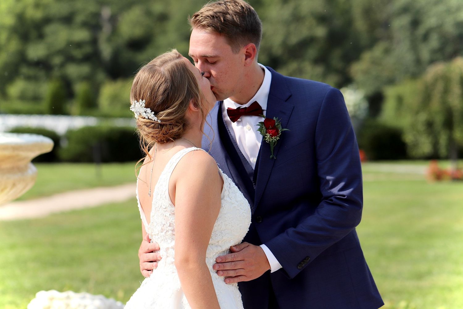 Bride and groom sharing a romantic first kiss outdoors at a garden wedding ceremony.