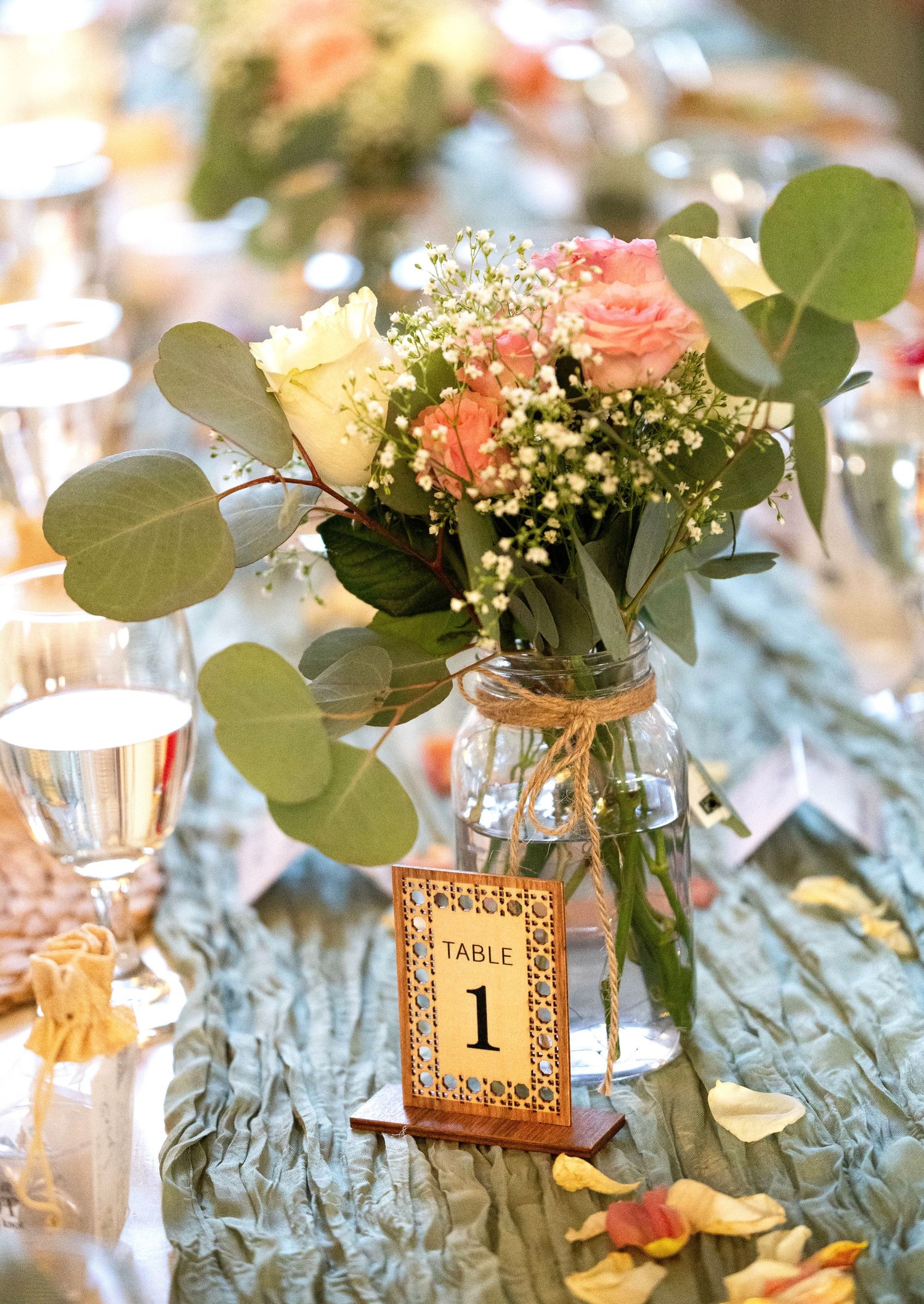 Rustic wedding centerpiece with peach roses baby breath eucalyptus in mason jar table one.