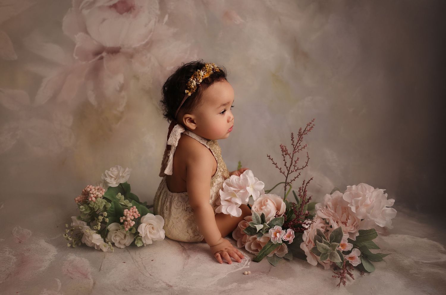 Child sitting on floor surrounded by flowers milestone photoshoot