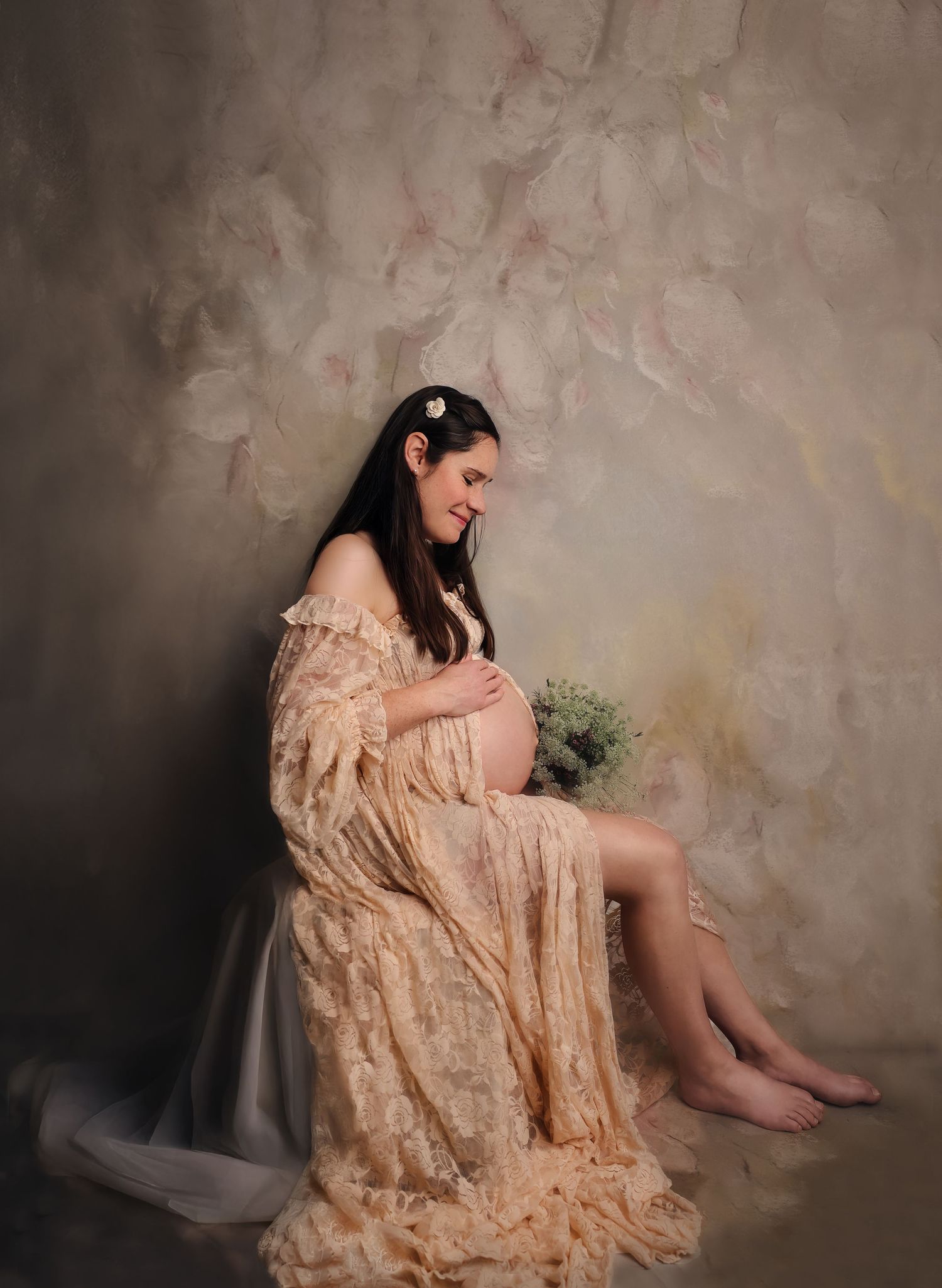 Pregnant woman sitting holding her belly in study photoshoot