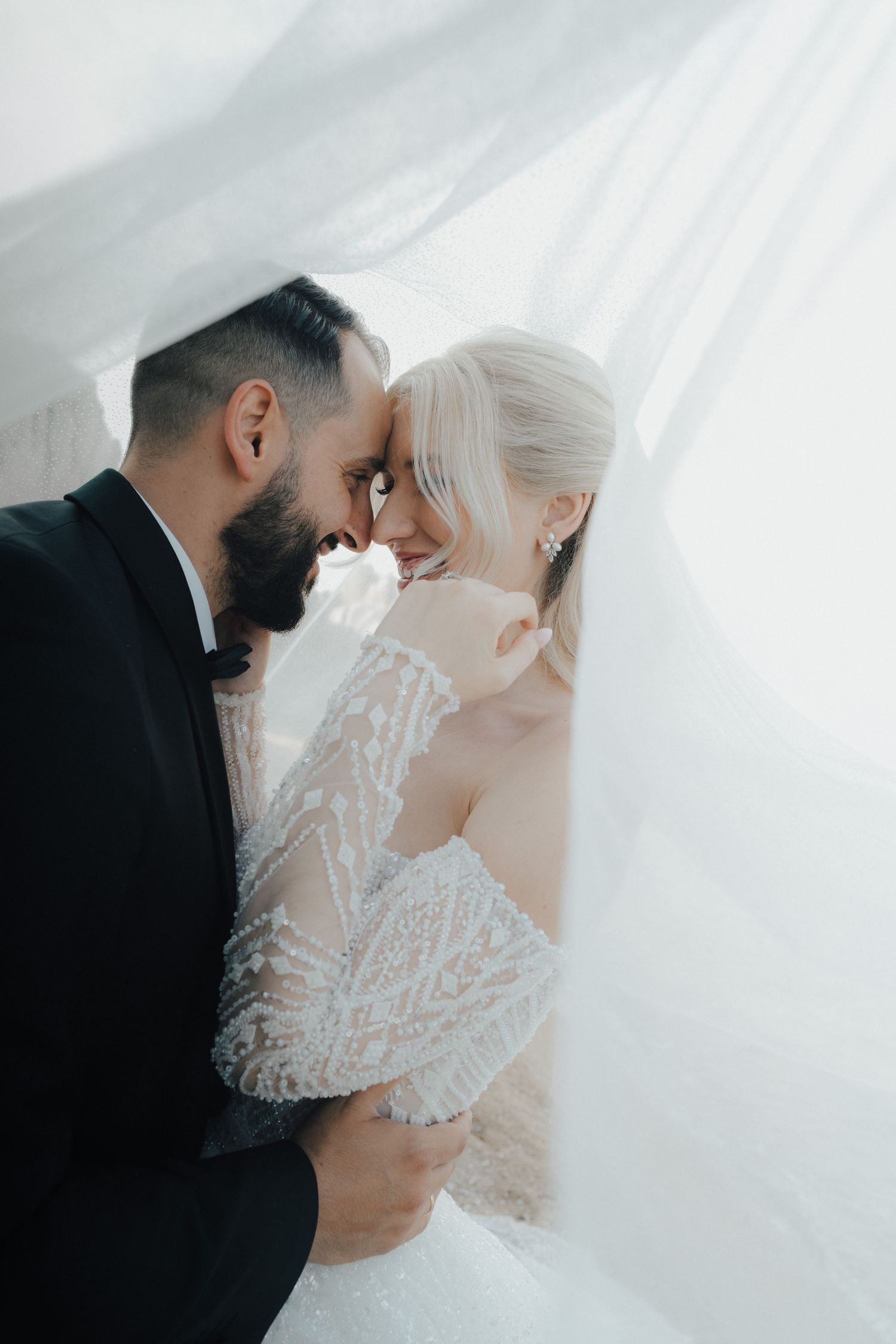 An intimate wedding portrait with flowing veil and soft natural light.