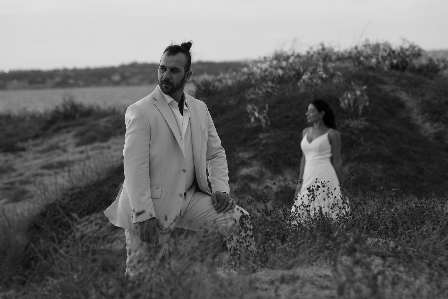 Black and white wedding photos show couple embracing in a scenic outdoor meadow setting.