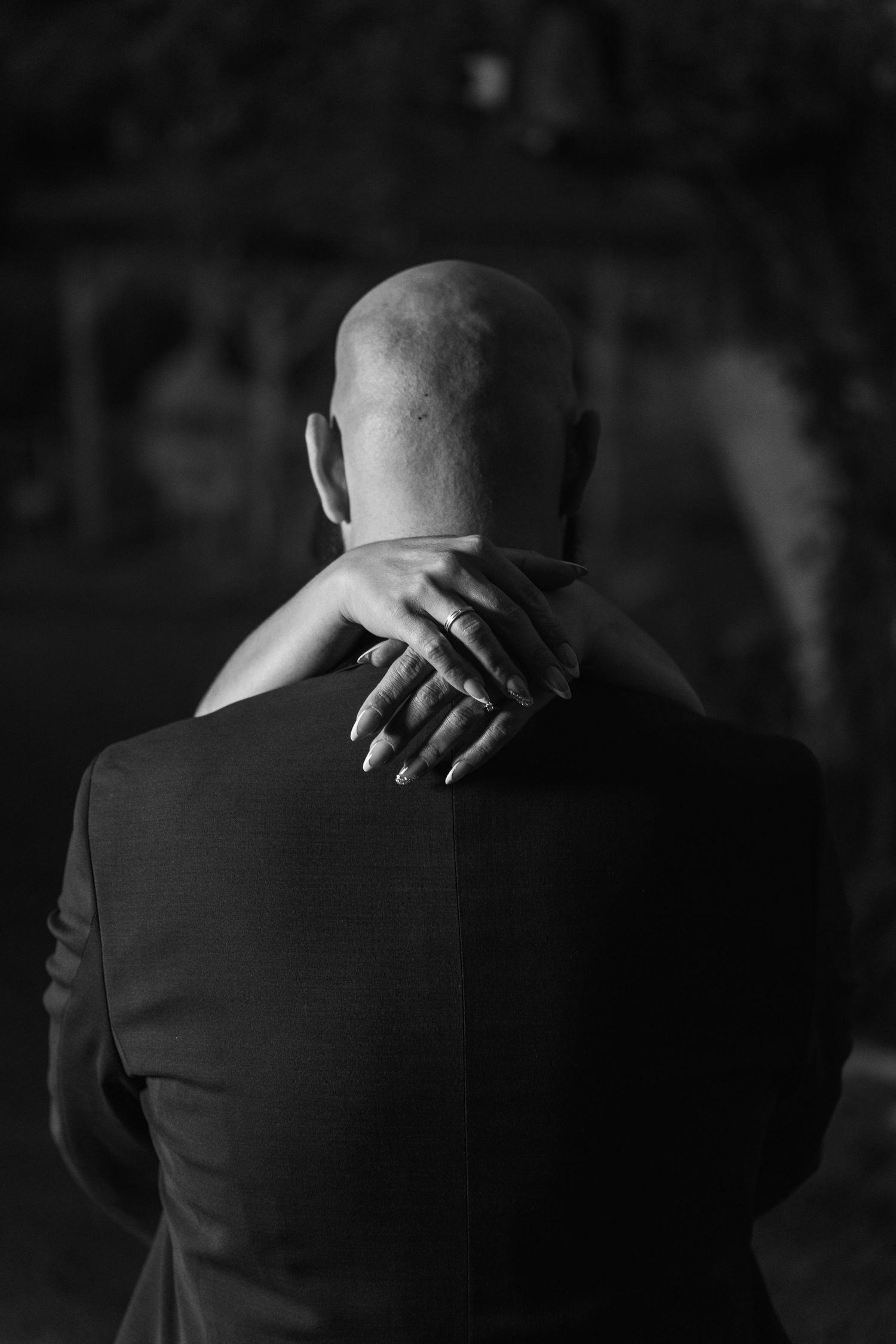 A black and white sequence showing a person's back and shoulders in five similar poses with hands resting on shoulders.