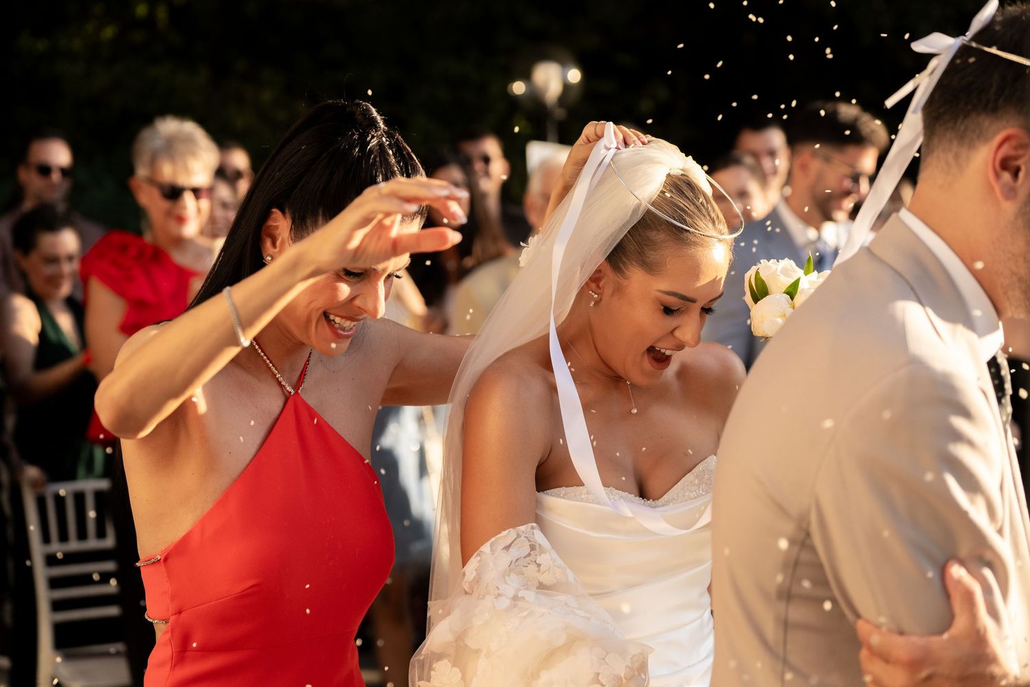 Wedding party celebrates outdoors with champagne spraying and festive reactions during sunset celebration.