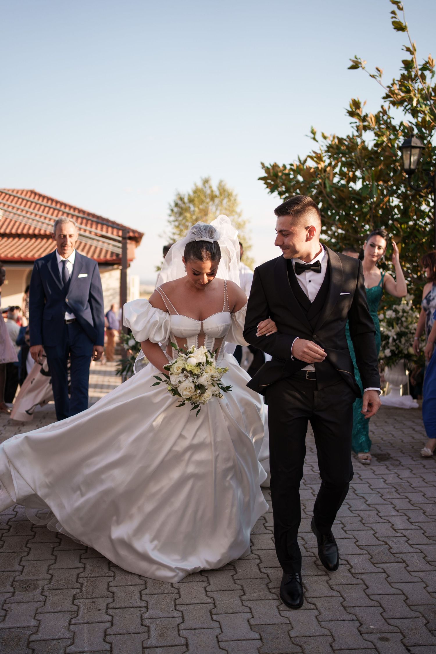 Sequence of wedding photos showing couple walking and dancing together on stone patio with Spanish-style architecture.