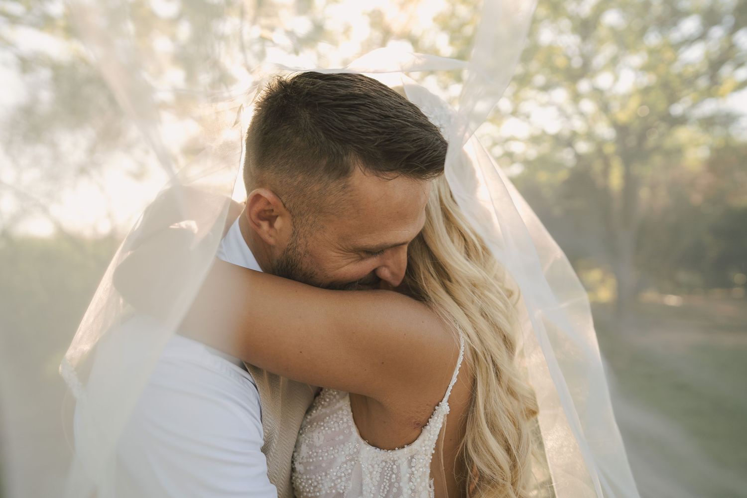 Sun-drenched wedding portraits of a couple sharing intimate moments in a forest setting.