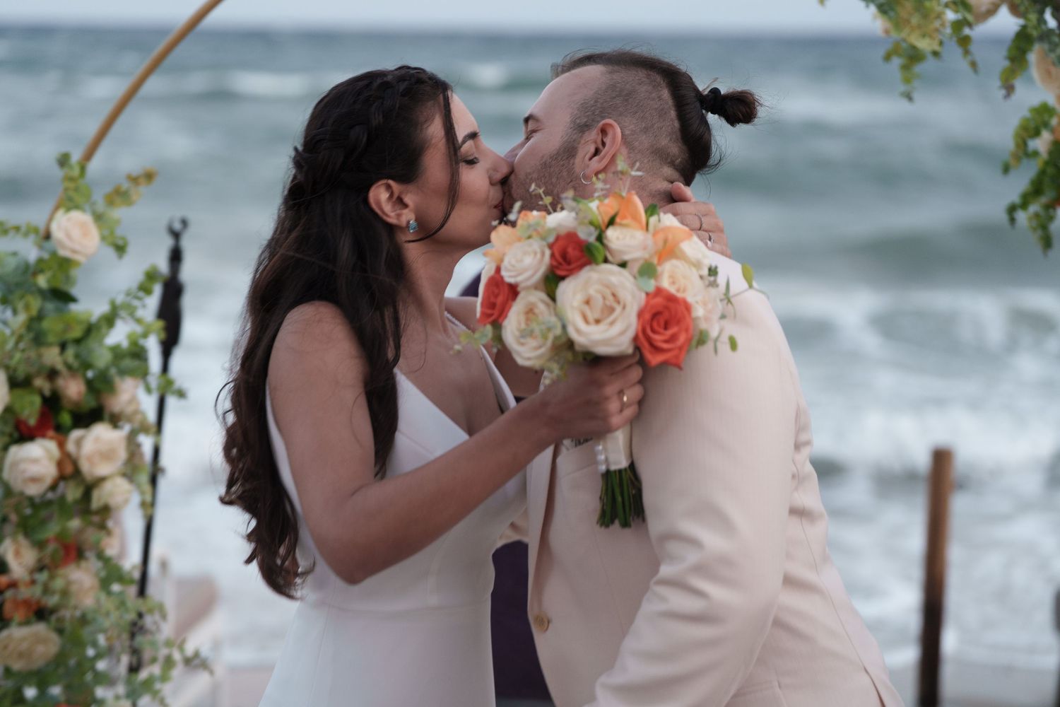 A romantic beach wedding ceremony with floral decorations and waves crashing in the background.